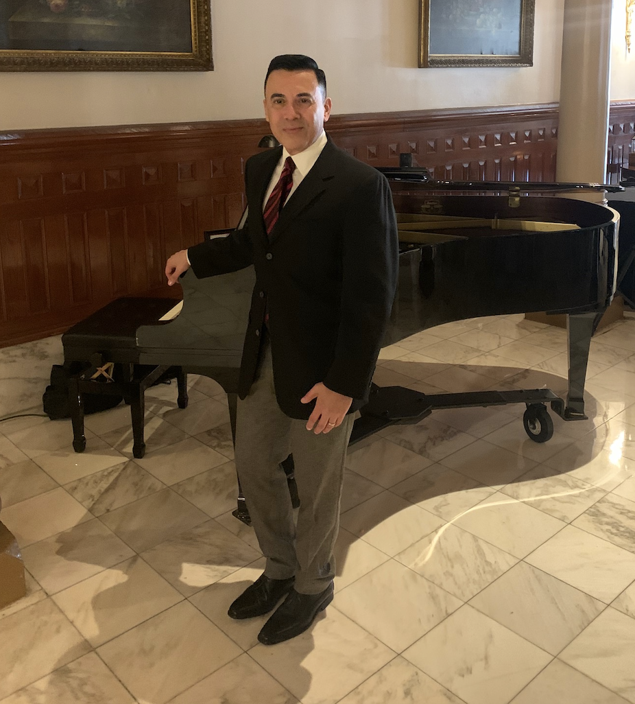Aaron standing in front of piano in San
                        Antonio